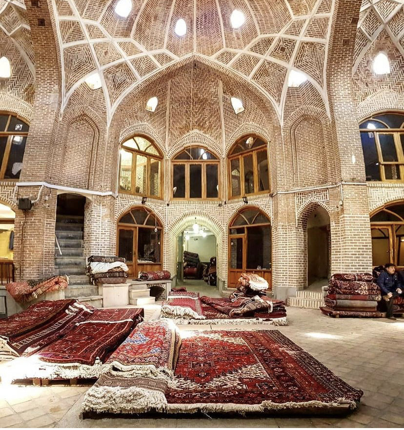 A traditional market setting with numerous ornate rugs laid out on the floor, representing the products of Accents Galleria in Kansas City, MO