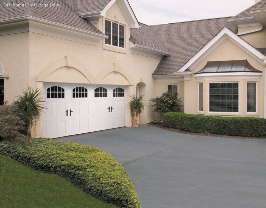 A traditional white garage door with arched windows on a stucco home, installed by CCM Overhead Doors in Oklahoma City, OK.