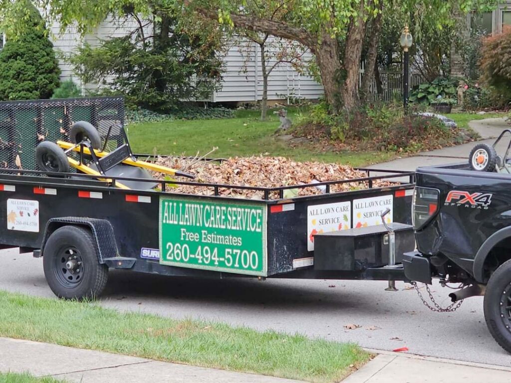 A utility trailer loaded with leaves and landscaping tools for ALL Lawn Care Service in Saint Louis, MO