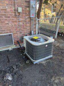 An outdoor Trane AC unit installed next to a brick residential building by JM HVAC Pros in Elgin, IL.