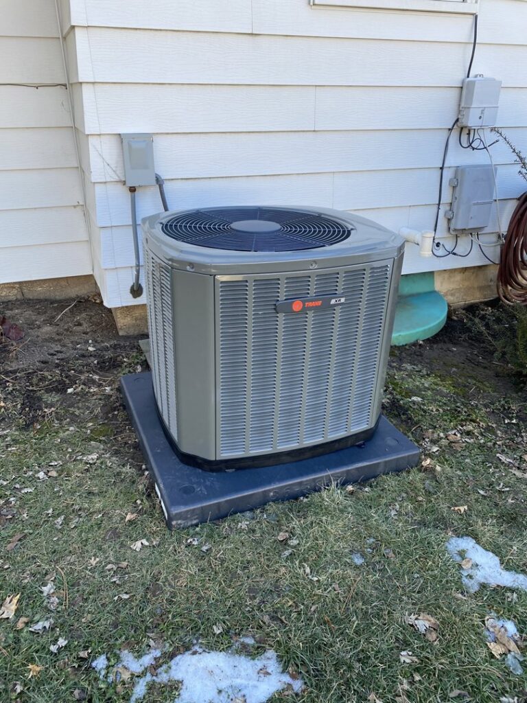 A Trane air conditioning unit installed next to a house during winter by Comfort Solutions Heating and Air Conditioning in Omaha, NE.