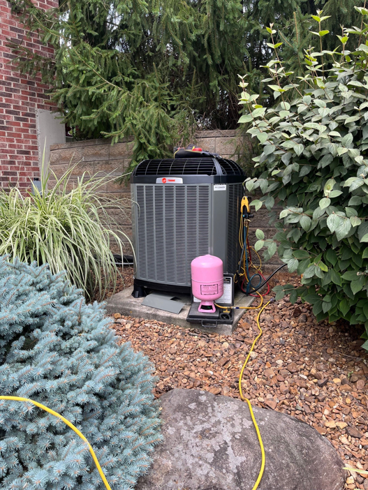 An outdoor Trane AC condenser unit undergoing maintenance with gauges and hoses connected by Tri County Heating and Cooling in Longmont, CO.