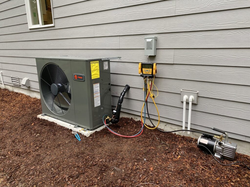 A Trane HVAC outdoor unit being installed or serviced with gauges and vacuum pump by Climate Control Experts HVAC LLC in Federal Way, WA