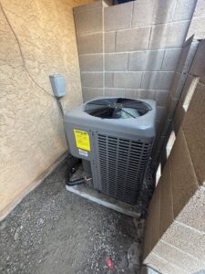A Trane outdoor air conditioning condenser unit installed next to a block wall by HoxAir Heating & Cooling in Phoenix, AZ