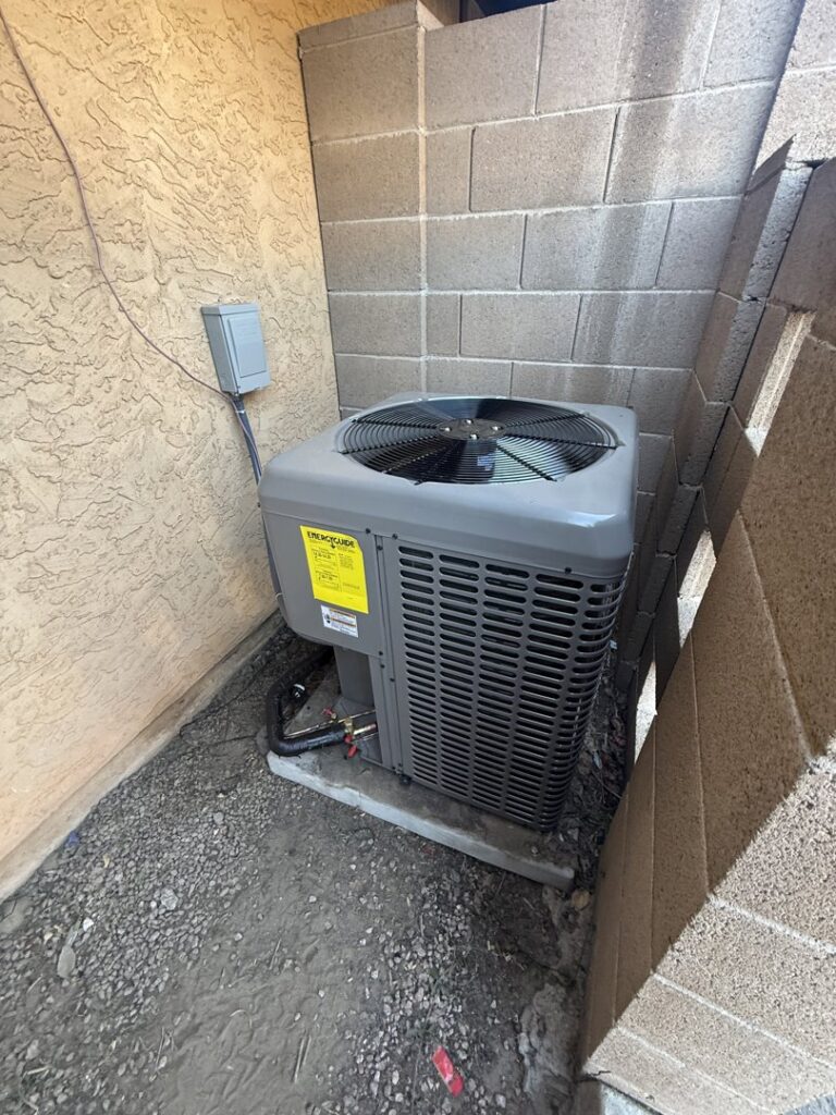 A Trane outdoor air conditioning condenser unit installed next to a block wall by HoxAir Heating & Cooling in Phoenix, AZ