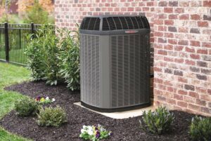A Trane outdoor air conditioning unit installed next to a brick wall by Strine's Heating & A/C in York, PA.