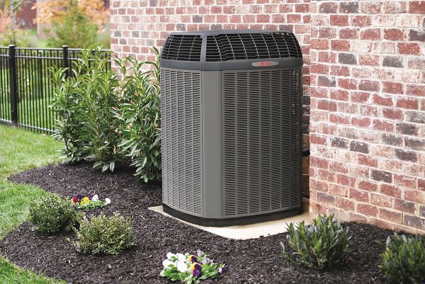 A Trane outdoor air conditioning unit installed next to a brick wall by Strine's Heating & A/C in York, PA.