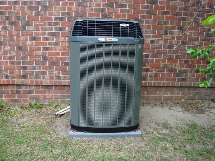 An outdoor Trane HVAC condenser unit installed next to a brick building by Berkeley Heating and Air Conditioning in Hanahan, SC