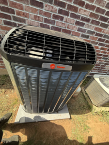 An outdoor Trane HVAC unit installed next to a brick wall by Ice Cold A/C & Heating in Bossier City, LA.