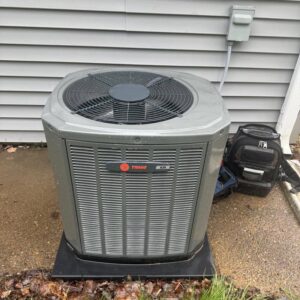 An outdoor Trane XR AC condenser unit with a technician's tool bag nearby, serviced by Hodges Heating & Cooling in Owensboro, KY.