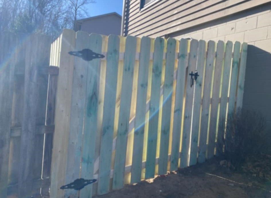 A treated wood fence gate with black hardware installed by Fencing Company Of Omaha in Omaha, NE.