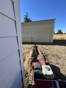 A trenching machine digging a trench for underground electrical lines by Circuit Masters, Inc. in Billings, MT.