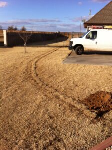 A trench dug in a residential yard for underground electrical conduit installation by Generator Experts of Oklahoma in Norman, OK.