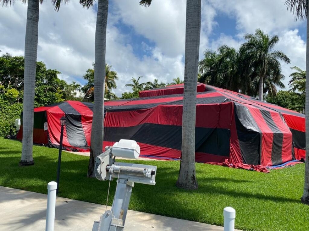 A tropical home covered in a red and black fumigation tent by PNP Pest Solutions LLC in Miami, FL.