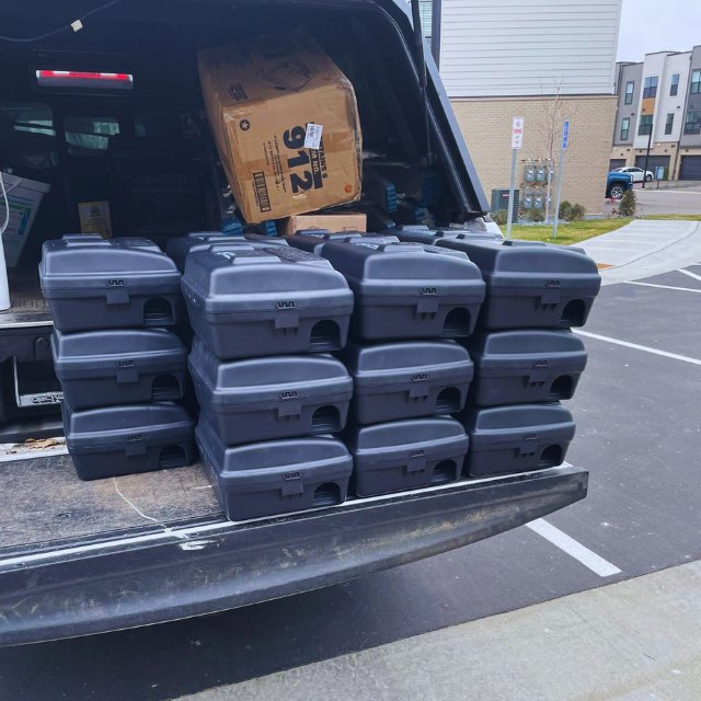 A truck bed loaded with multiple black rodent bait stations for pest control services by 1st Choice Pest Solutions in Eau Claire, WI.