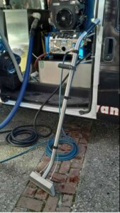 Truck-mounted carpet cleaning equipment with a wand and hoses ready for a job by Advanced Carpet Cleaning in College Station, TX