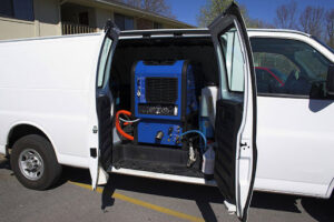 A white service van with its doors open, revealing a blue truck-mounted carpet cleaning machine for Lincoln Carpet Cleaning Pros in Lincoln, NE.