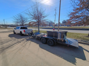 A white pickup truck towing a trailer loaded with fencing materials for Fence Experts STL in Fenton, MO