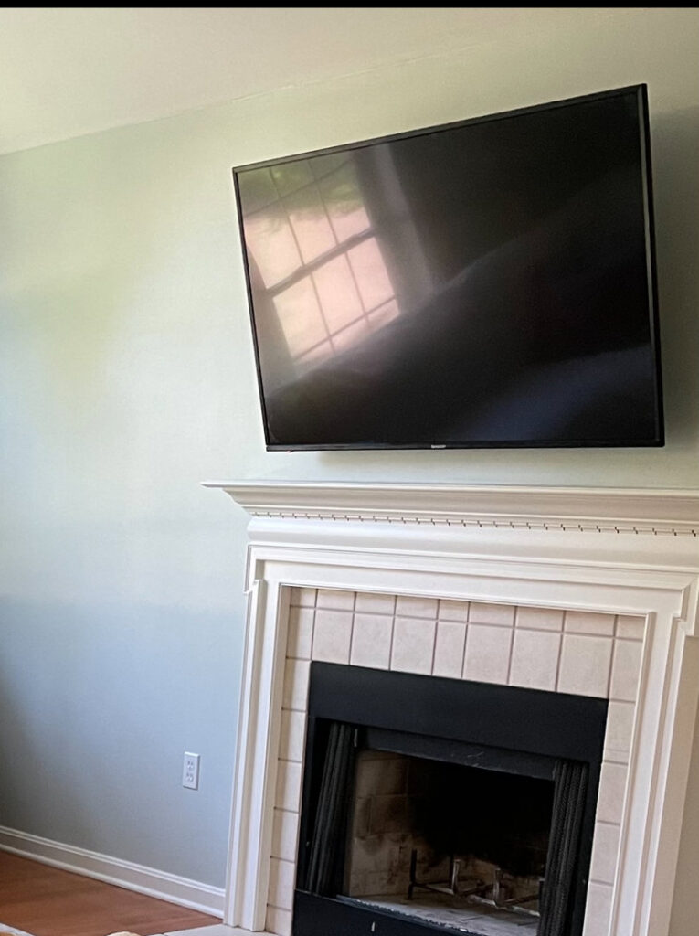 Professionally wall-mounted television above a fireplace with a new electrical outlet installed by Golden Electric in Danbury, CT.