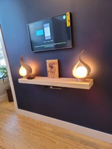 Wall-mounted TV with hidden wiring and floating shelf installed by Julio A Lopez Electrician in Lowell, MA.