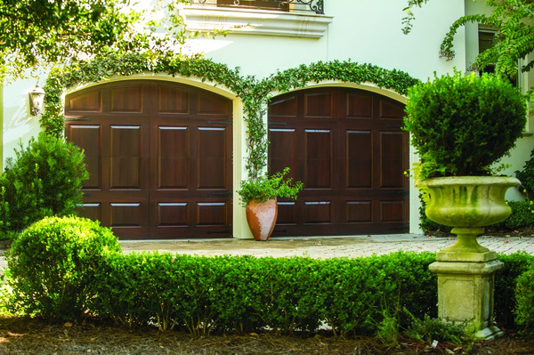 Two arched dark wood garage doors on a residential home by Overhead Door Company of the Great Plains in Lawton, OK.