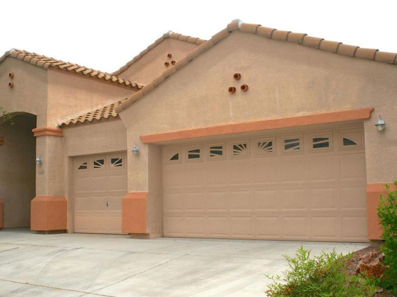 Two beige garage doors with decorative windows on a residential home, installed by Johns Garage Doors in Tucson, AZ.