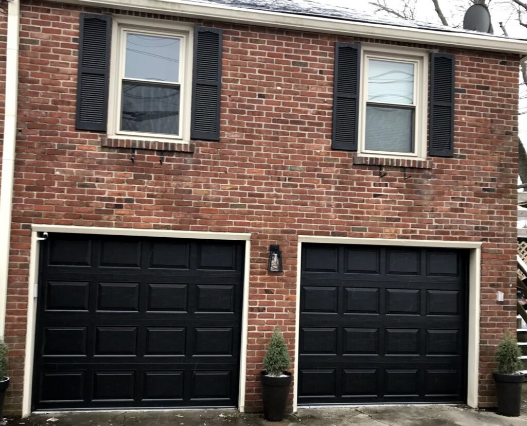 Two black panel garage doors installed on a brick residential house by Affordable Overhead Garage Door in Modesto, CA