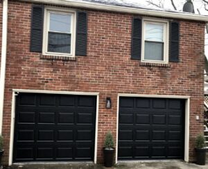 Two black panel garage doors installed on a brick residential house by Affordable Overhead Garage Door in Modesto, CA