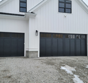 A house exterior featuring a single and a double black panel garage door, installed by Southcoast Overhead Door & Services in Fall River, MA.