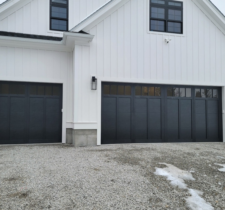 A house exterior featuring a single and a double black panel garage door, installed by Southcoast Overhead Door & Services in Fall River, MA.