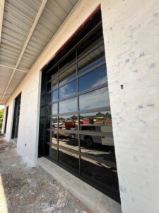 Two black panel garage doors installed on a new construction building by Signature Garage Doors in Huntsville, AL.