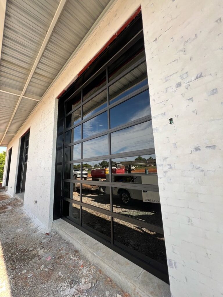Two black panel garage doors installed on a new construction building by Signature Garage Doors in Huntsville, AL.