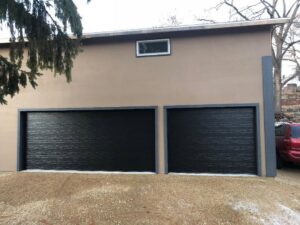 Two sleek black textured garage doors installed on a modern building, a service from Madison Overhead Garage Door Services in Madison, WI.