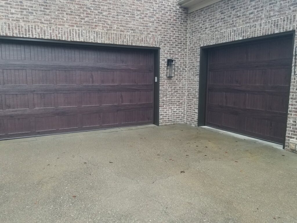 Two brown garage doors, one large and one small, on a brick home, installed by Door-Tech LLC in Lexington, KY.