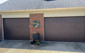 Two matching brown garage doors with panel designs on a brick home by Overhead Door Company of Evansville in Evansville, IN.