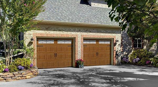 A brick house showcasing two new brown garage doors with decorative windows from Frankfort Overhead door Sales & Service in Frankfort, KY