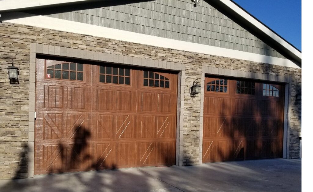 Two brown garage doors with arched windows on a stone and siding house by SCI Door in Yakima, WA
