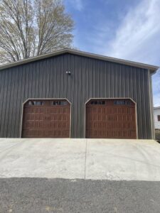 Two brown panel garage doors installed on a brick house by Skylift Garage Doors - Knoxville, TN