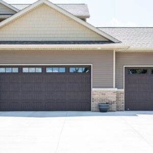 Two brown panel garage doors with windows installed on a modern home by Calavera Garage Doors in Mesa, AZ