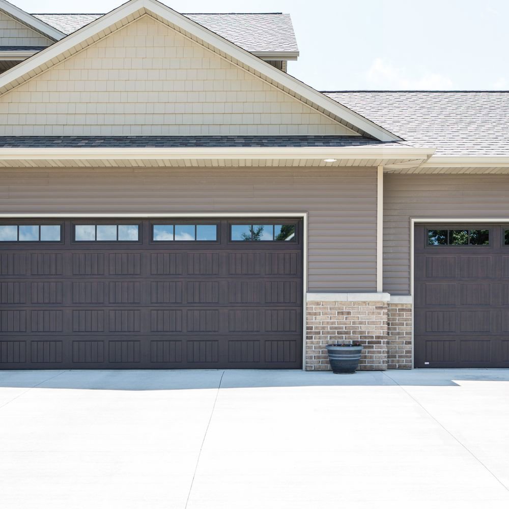 Two brown panel garage doors with windows installed on a modern home by Calavera Garage Doors in Mesa, AZ
