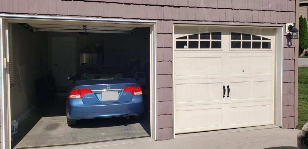 A two-car garage featuring one open door with a car inside and one closed door with decorative windows, serviced by Knox Garage Door Service LLC in Knoxville, TN.