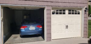 A two-car garage featuring one open door with a car inside and one closed door with decorative windows, serviced by Knox Garage Door Service LLC in Knoxville, TN.