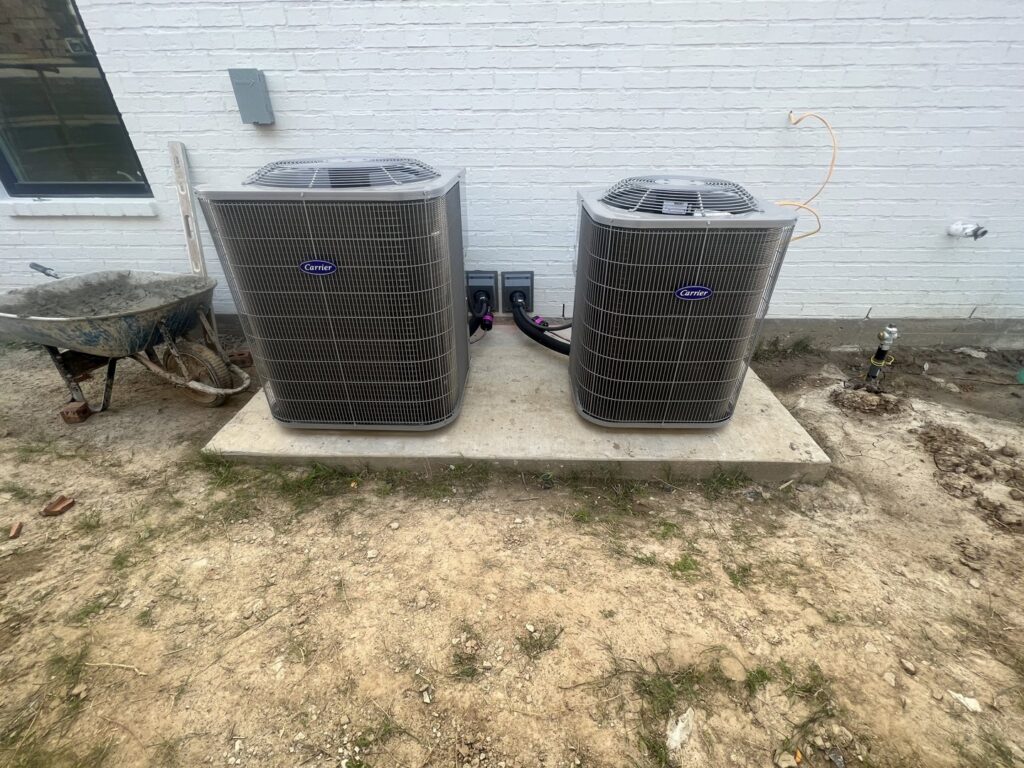 Two Carrier brand HVAC condenser units installed on a concrete pad by Alpha HVAC LLC in Alexandria, LA.