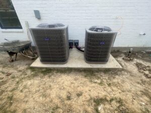 Two Carrier brand HVAC condenser units installed on a concrete pad by Alpha HVAC LLC in Alexandria, LA.