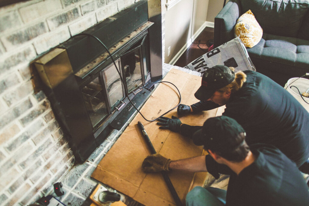 Two chimney sweeps from Soot Busters working together on a fireplace insert in a client's home in Birmingham, AL.