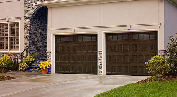 A modern house featuring two dark brown panel garage doors with windows from Frankfort Overhead door Sales & Service in Frankfort, KY