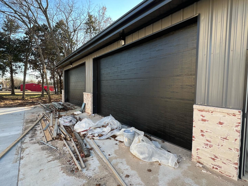Two dark-colored garage doors on a commercial building, showing a recent installation by Hometown Garage Doors in Crestview, FL.