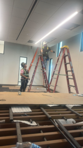 Two skilled electricians from Reyes Electric Company installing ceiling lights and fixtures in Dallas, TX.