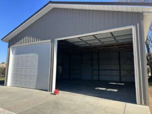 Two garage doors, one open and one closed, installed on a metal building by Rose Quality Garage Doors in Murfreesboro, TN