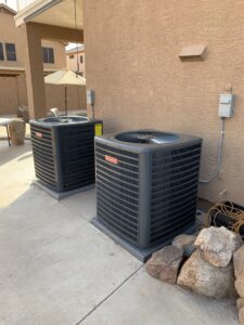 Two Goodman outdoor condenser units installed next to a residential building by Valle Del Sol Home Services, LLC in Scottsdale, AZ.